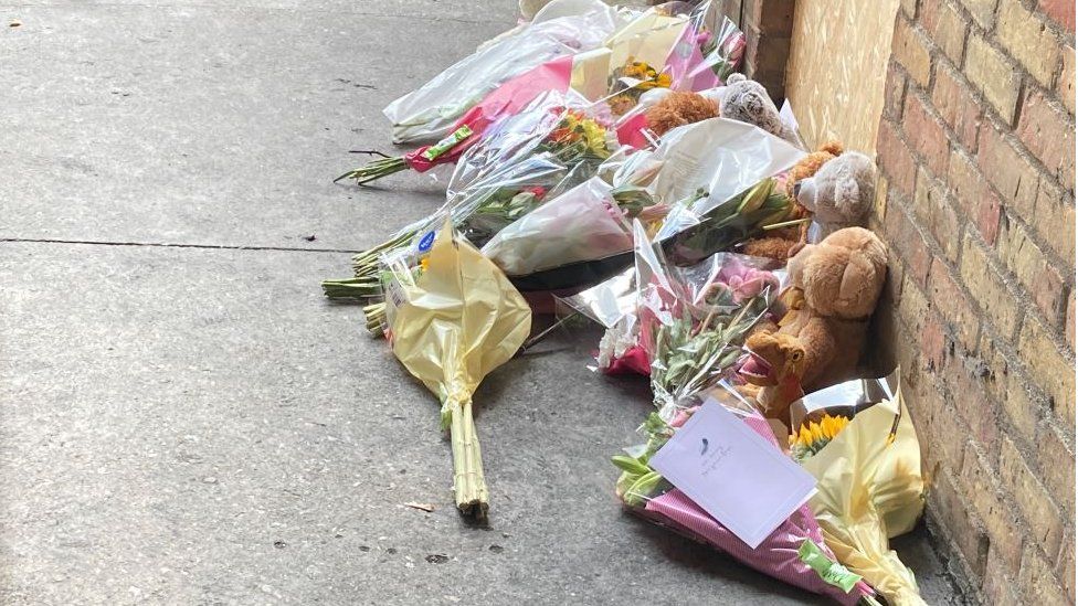 Flowers and soft toy bears at the scene of a house fire