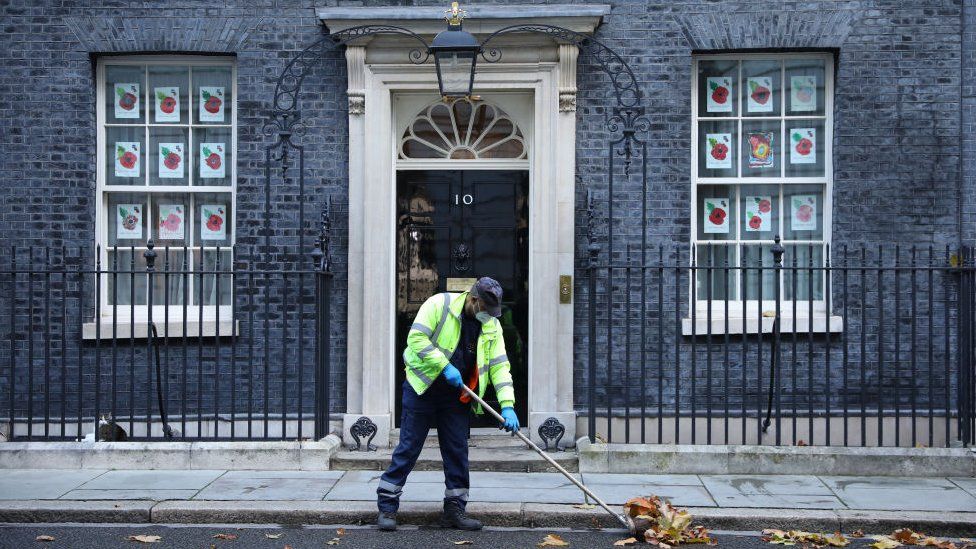 A worker sweeps leaves outside 10 Downing Street