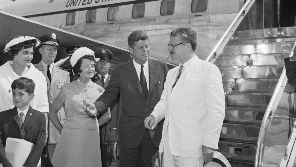 President Kennedy chats with Ecuadorean President Julio Arosemena, (extreme right), as they pose for cameraman at Washington National Airport, July 1962