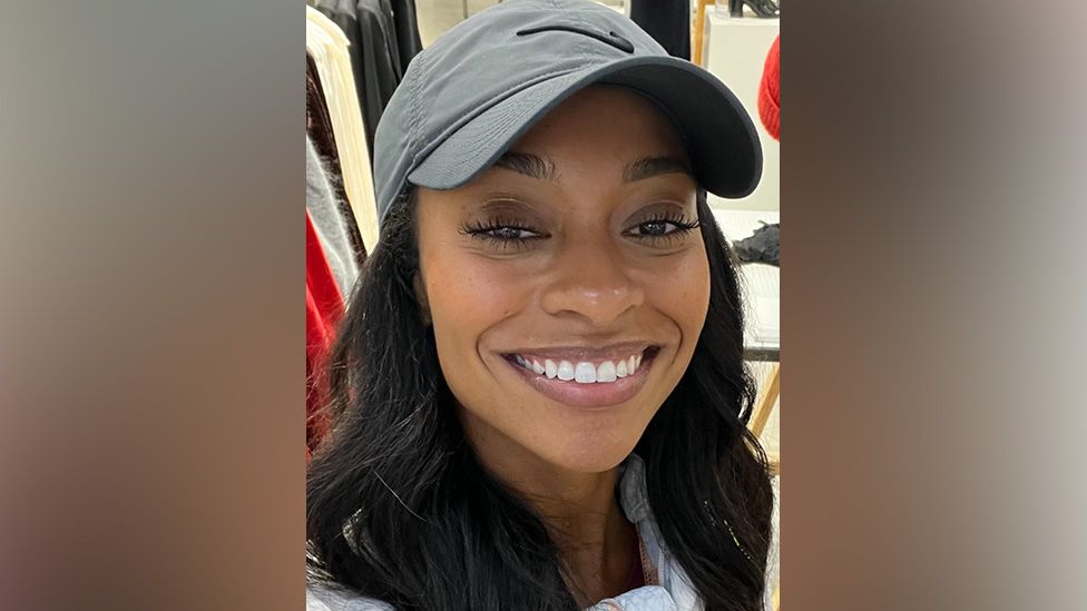 Liz Lafontant smiling in a selfie, her hair is down and she's wearing a baseball cap