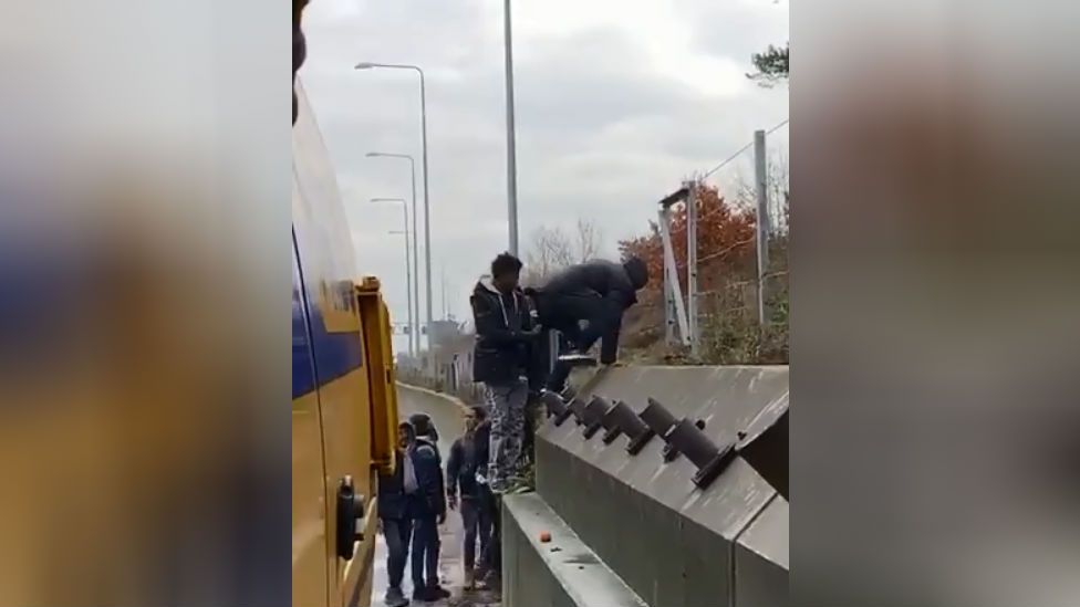 Migrants climb up embankment