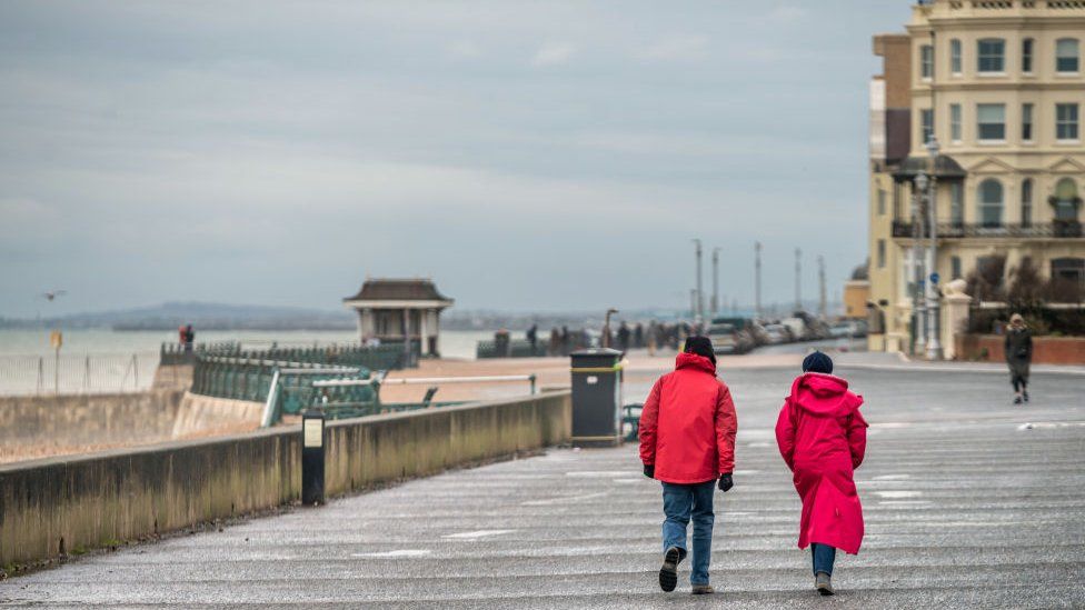 Two people walk during lockdown on Brighton's sea front on 26 January