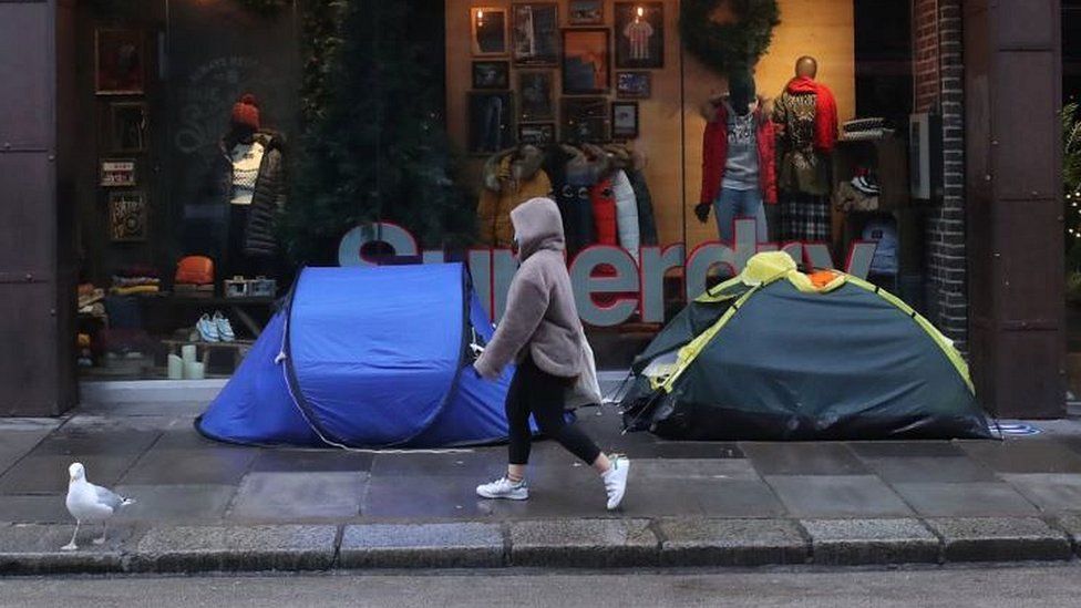 A woman walks past the tents of homeless people