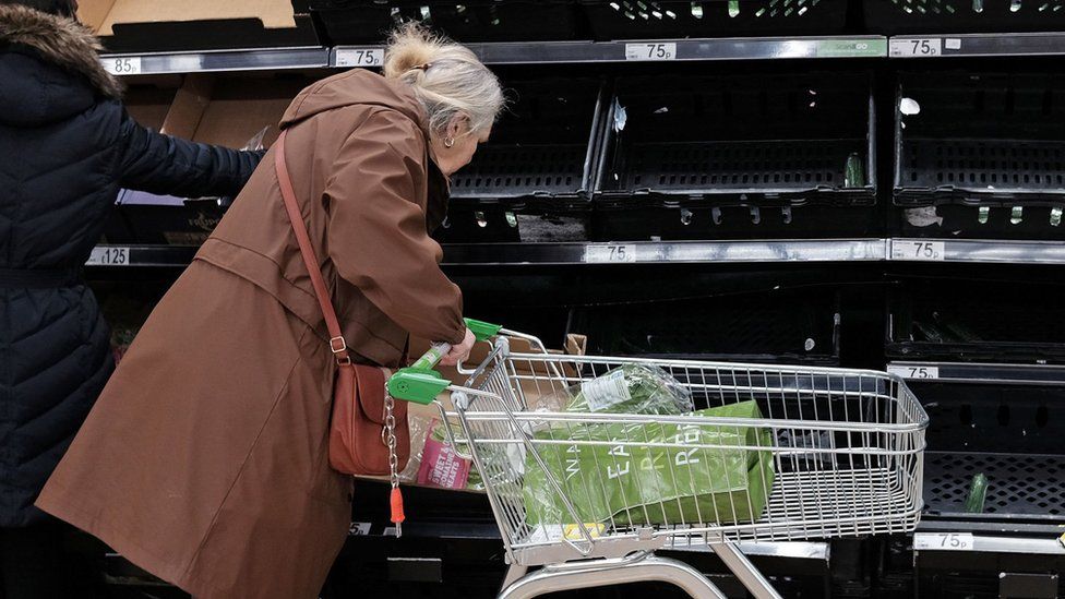 Woman in front of empty veg shelves