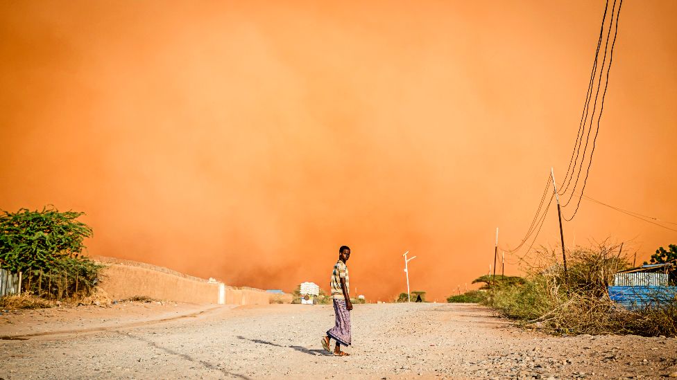 Mężczyzna idzie przed burzą piaskową w Dollow, południowo-zachodnia Somalia – kwiecień 2022 r