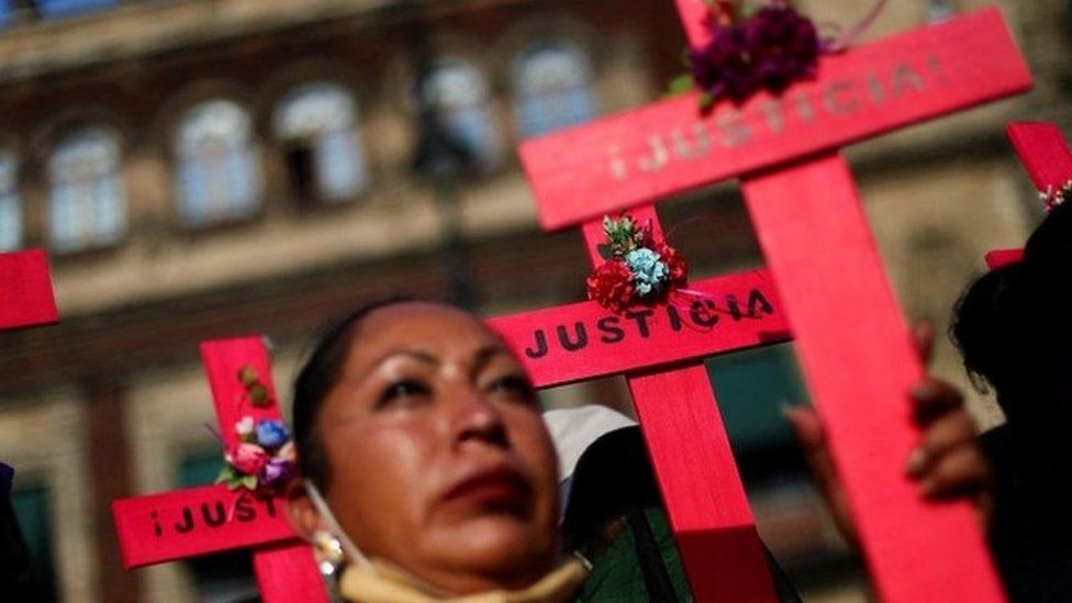 Женщины держат кресты в знак протеста против фемицида и насилия в отношении женщин возле Национального дворца в Мехико, Мексика, 18 мая 2022 г.