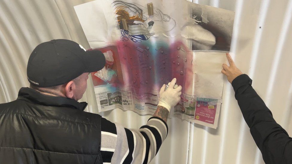 Man using a stencil to spray paint a design onto a wall