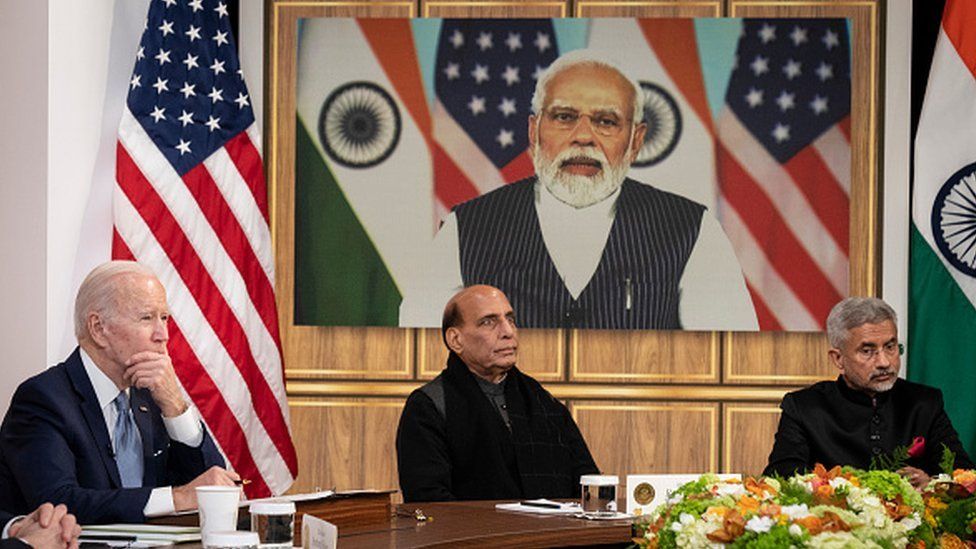 US President Joe Biden, Indian Minister of Defence Rajnath Singh, and Indian Foreign Minister S Jaishankar listen as Prime Minister Narendra Modi (on screen) speaks during a virtual meeting in the White House complex on 11 April 2022 in Washington, DC.