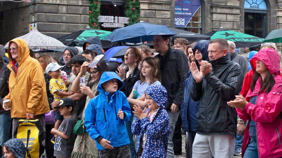 People watch a street performance in the rain at the Fringe festival in Edinburgh.