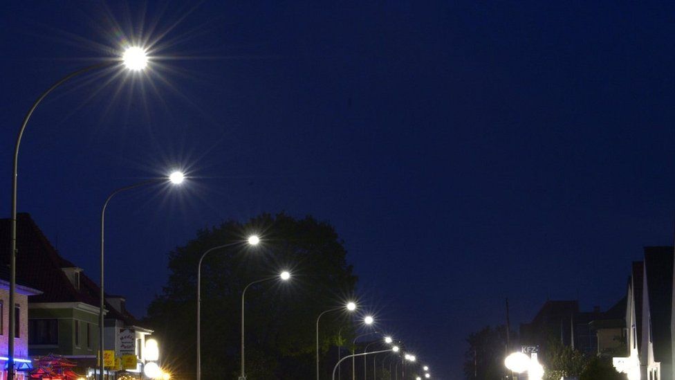 Light-emitting diode (LED) street lamps illuminate a road