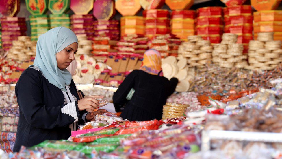 Женщины покупают сладости на рыночном прилавке в районе Сайеда Зайнаб в Каире, Египет (24 сентября 2023 г.)