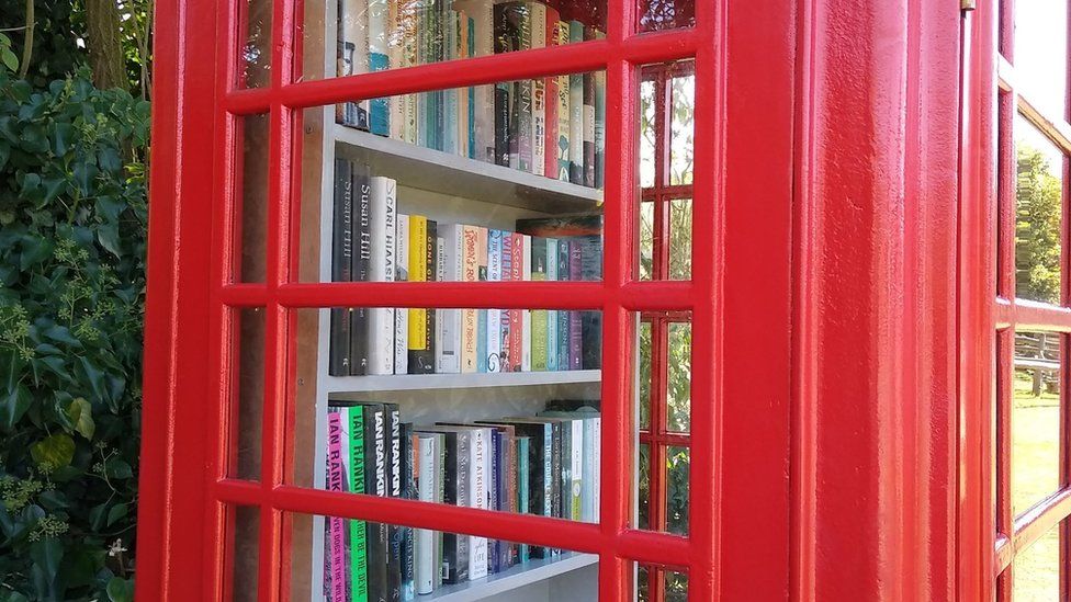 Books on shelves inside a red telephone box