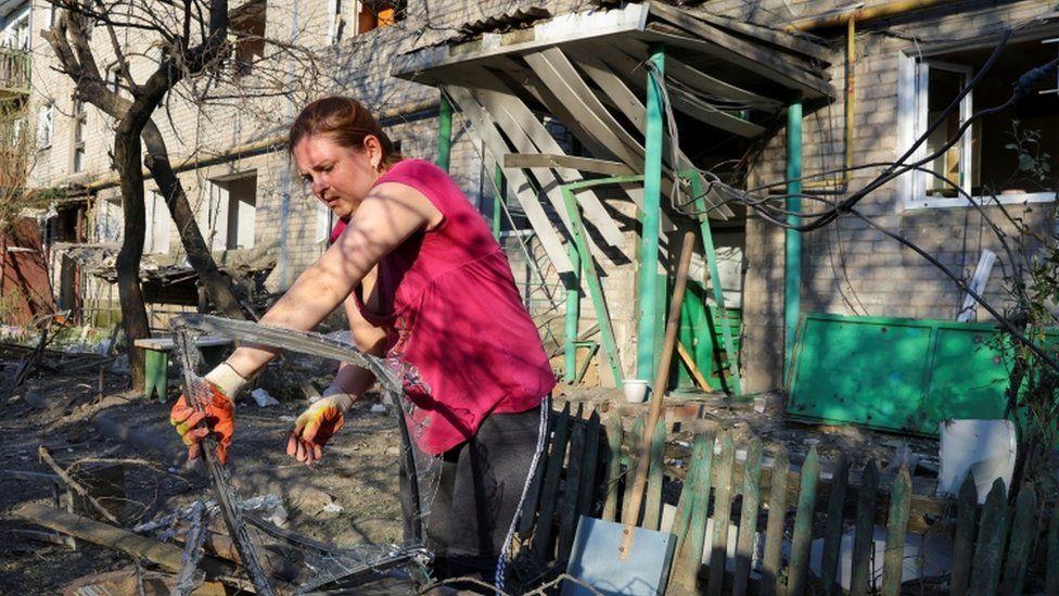 A local resident removes debris from a courtyard of an apartment building located in Vannikova street following recent shelling in the course of Ukraine-Russia conflict in Donetsk, Ukraine June 20, 2022