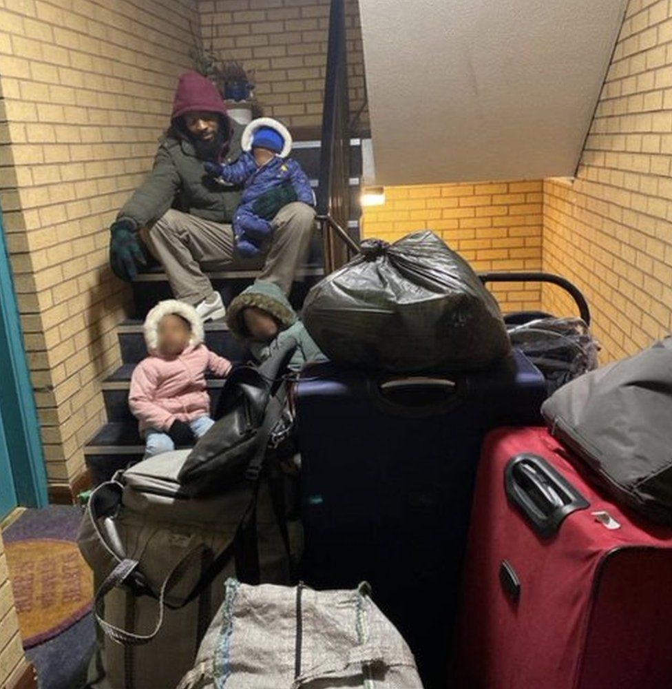 Henry and children with belongings on stairwell
