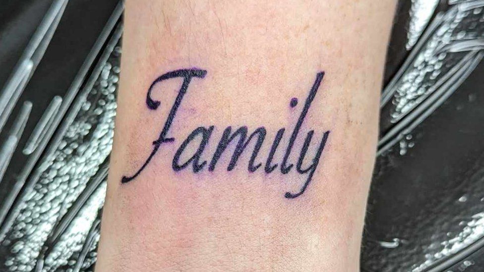 Wrist tattooed with the word 'family'.