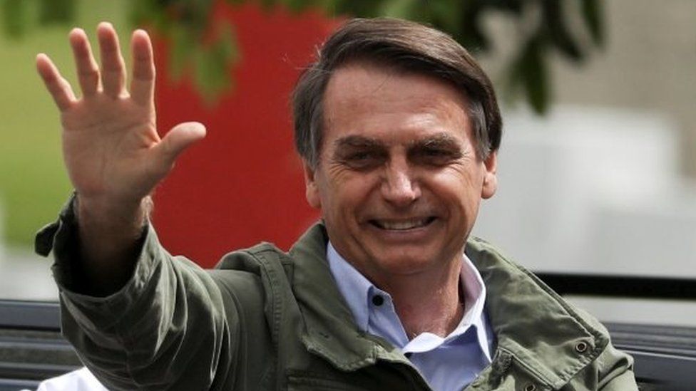Jair Bolsonaro waves at a polling station