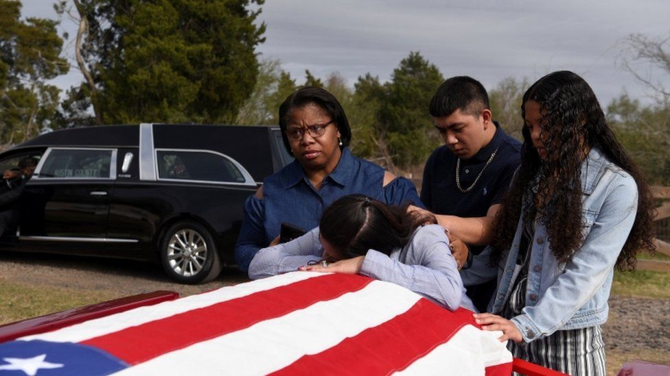 Семья прощается с задрапированным флагом гроба отца