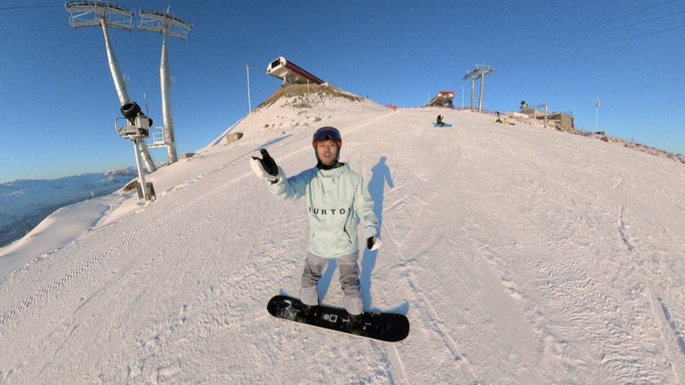 Китайский интернет-блогер Яо готовится спуститься на сноуборде с заснеженной горной вершины в Синьцзяне, Китай