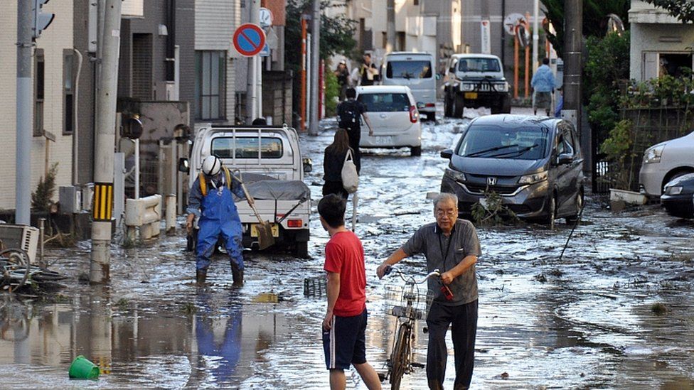 People walk in a street covered with mud in Kawasaki, near Tokyo, Japan, 13 October 2019