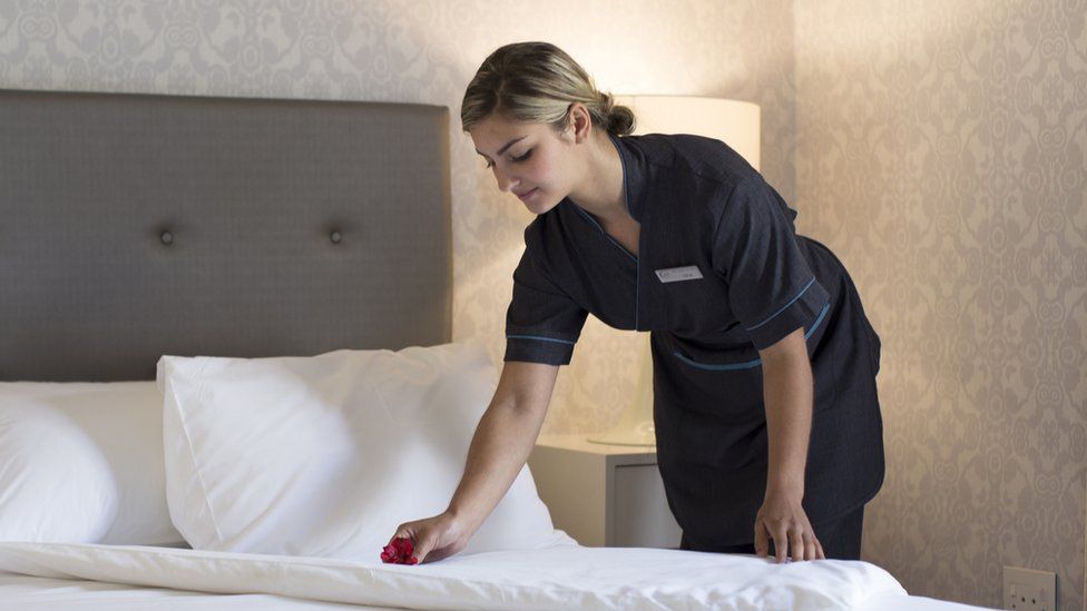 Chambermaid making up hotel room