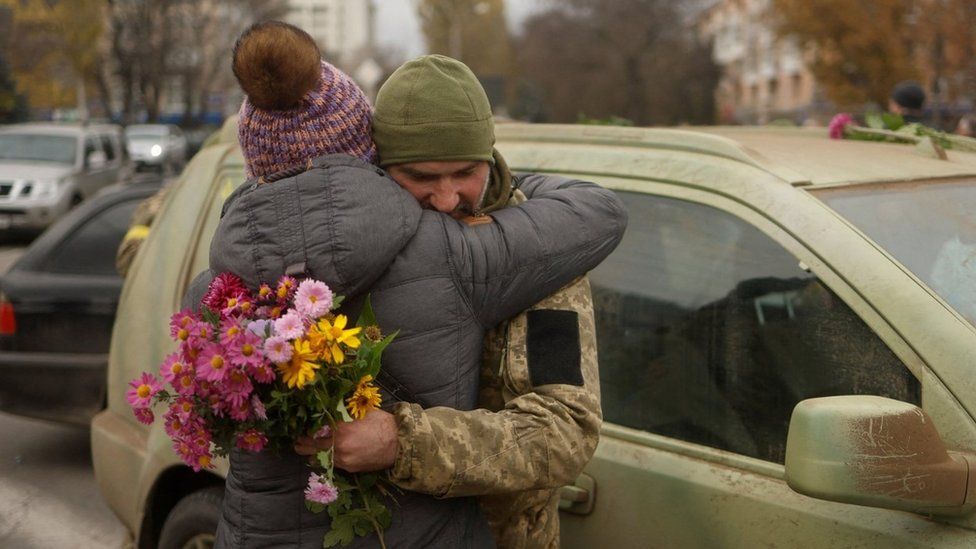 A Ukrainian soldier is hugged in Kherson