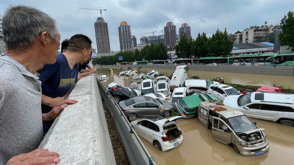 People look out at cars sitting in floodwaters after heavy rains hit the city of Zhengzhou