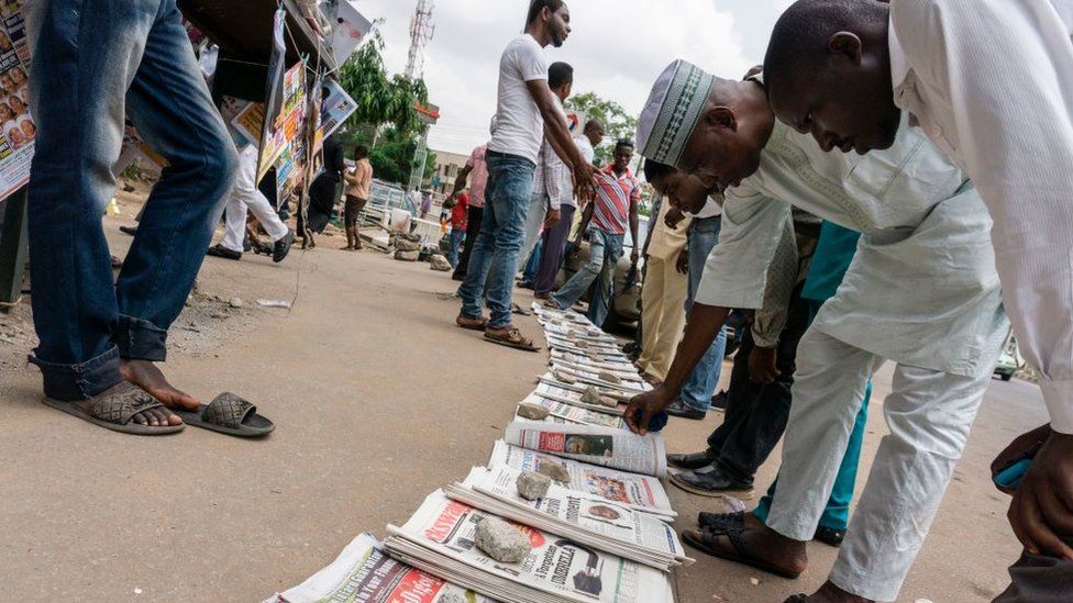 People read newspapers sold in the streets, which front pages focusing on Nigeria's President follow-up medical consultation in London and the release of eighty-two girls from Chibok, in Abuja on May 8, 2017