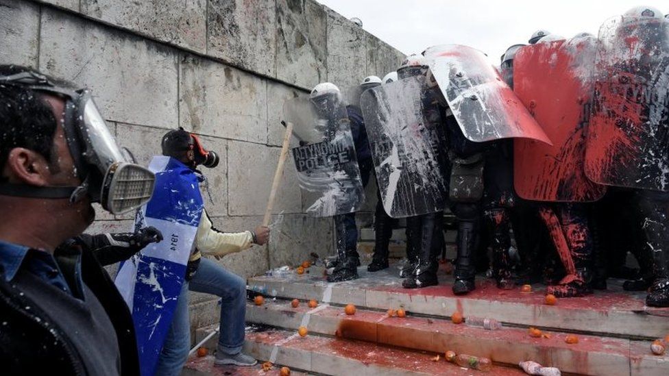 Protestors face off against police who have been doused in paint