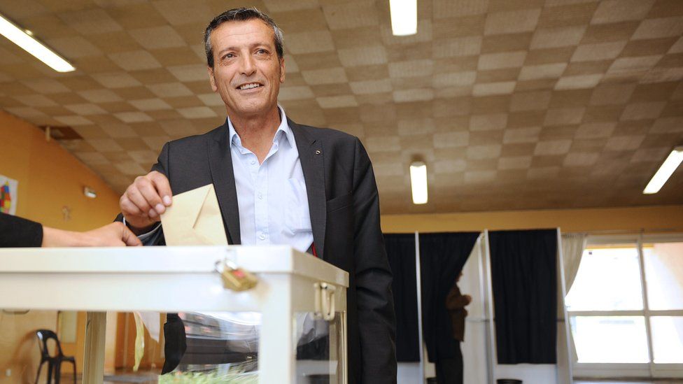 Edouard Martin votes in a centre while smiling at the camera in his election