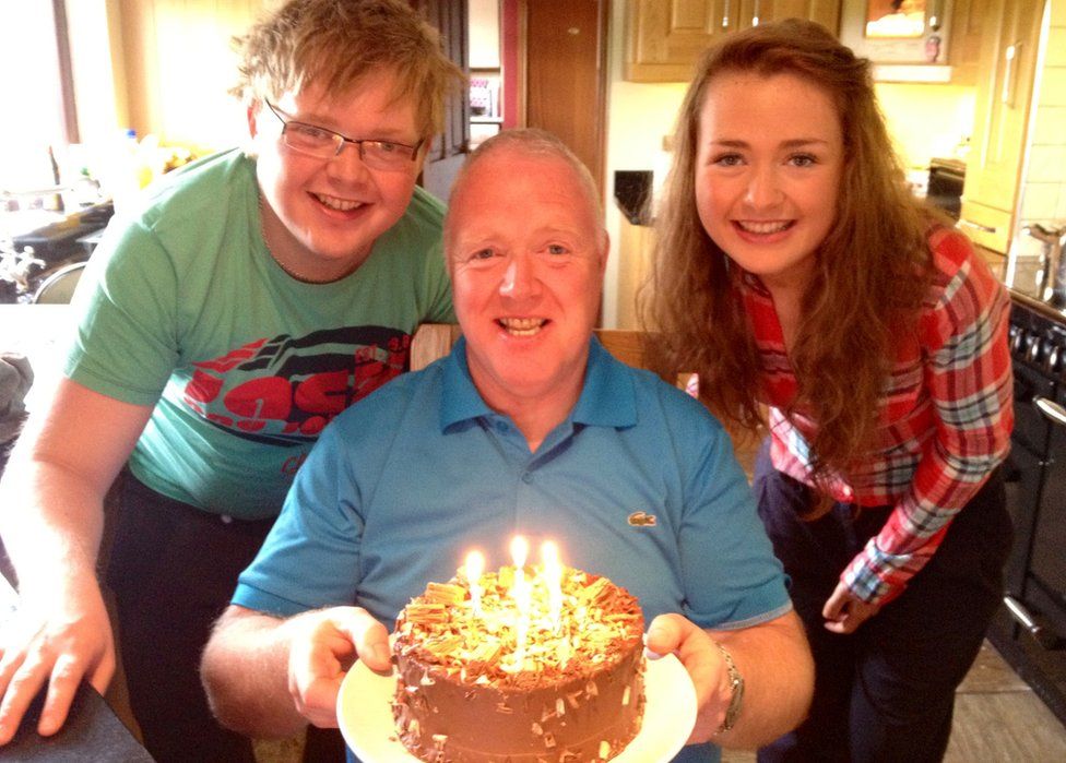 David Black holds a birthday cake while his son Kyle and daughter Kyla pose with him for a photograph