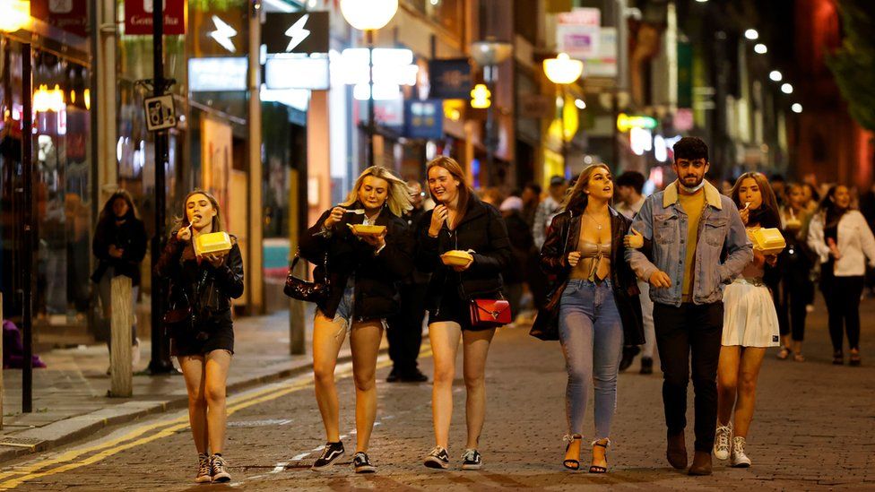 People walk outside bars in Liverpool before the new restrictions came into force