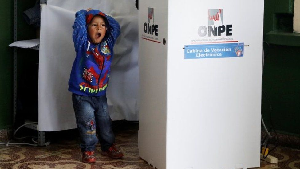 A child yawns while his mother casts her vote behind a voting booth in Peru's presidential election at a polling station in Lima, Peru, June 5, 2016.