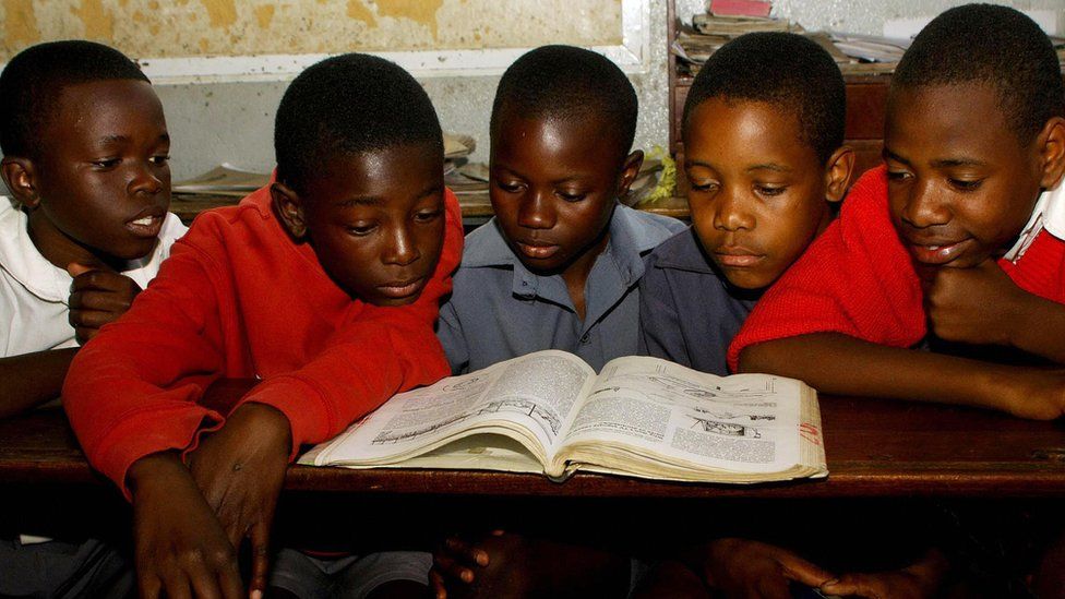 Zimbabwe pupils at a primary school in Zimbabwe's capital, Harare, read from the same textbook during a lesson on August 04, 2009