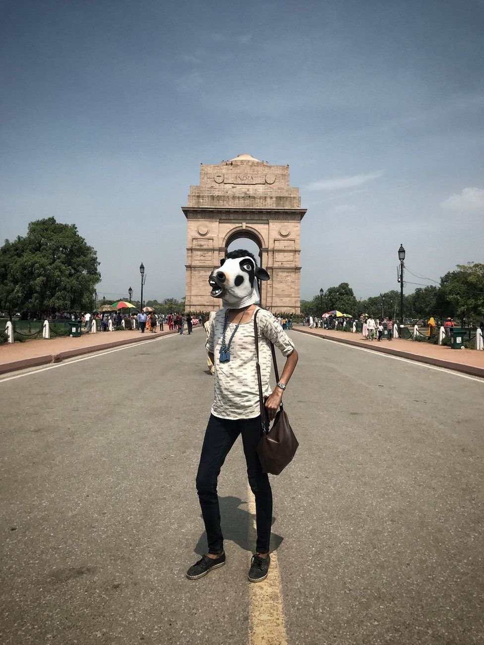 A woman with a cow mask in front of Delhi's India Gate