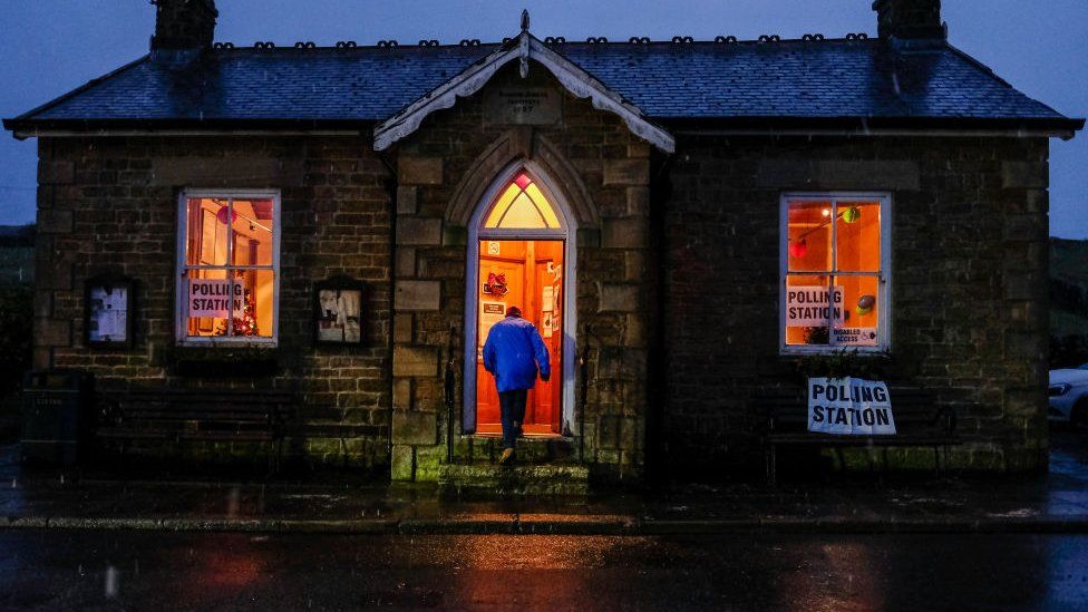 A man enters a polling station as snow falls in the North Pennines
