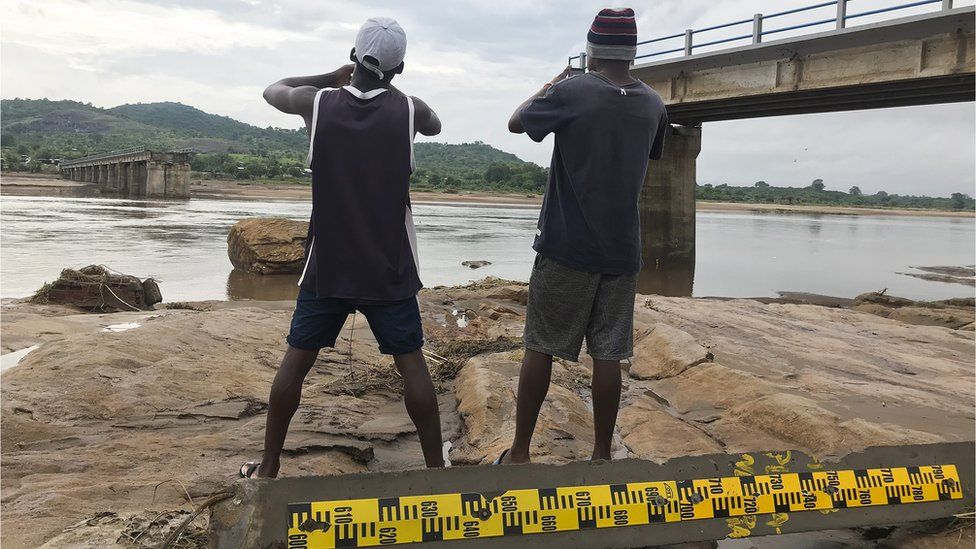 Two men take pictures of a destroyed bridge after Tropical Storm Ana hit the district of Tete, Mozambique, 27 January 2022