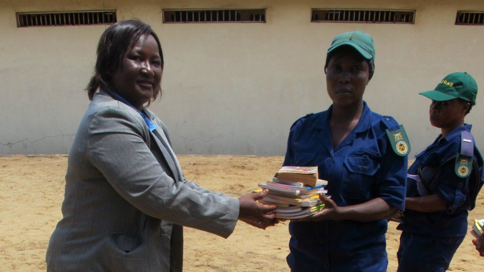 Woman hands books to prison guard