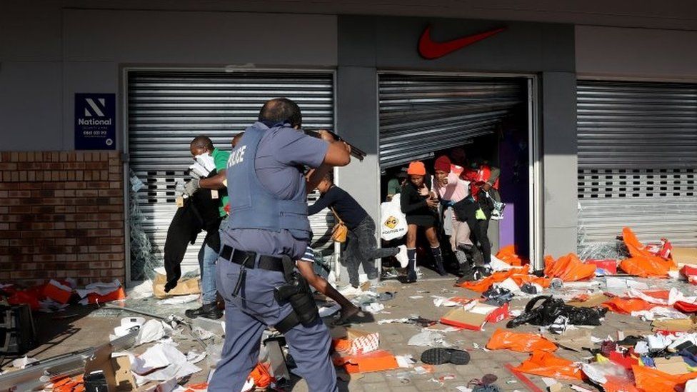 A member of the South African Police Forces tries to control looting during protests in Durban