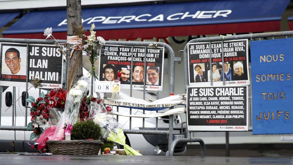 Flowers and messages in tribute to the victims of last year's January attacks are seen in front of the Hyper Cacher kosher supermarket at the Porte de Vincennes in Paris
