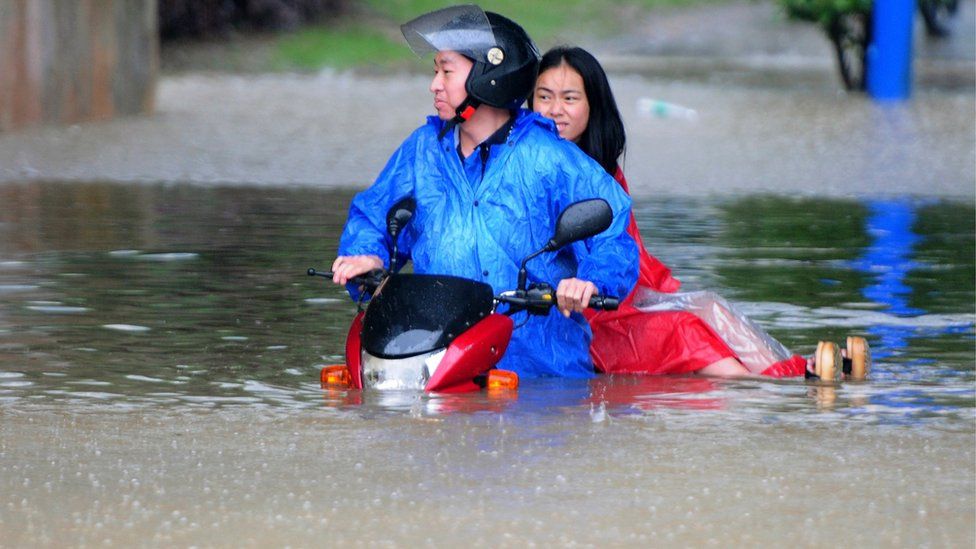 Jiangxi residents on a scooter in floodwater