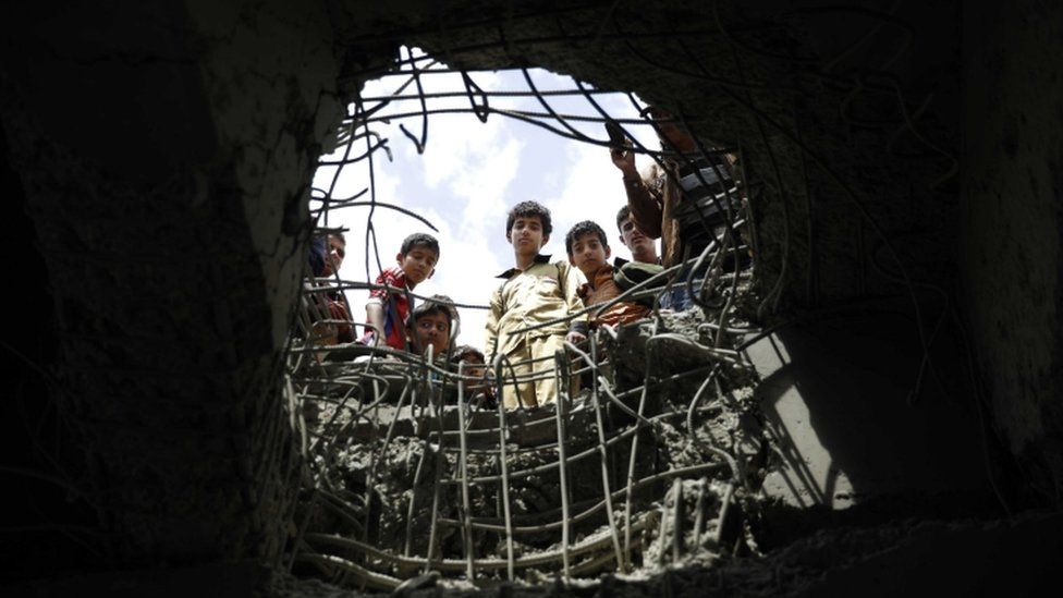 Boys look through a hole made by a Saudi-led airstrike on a bridge in Sana'a, Yemen, 23 March 2016
