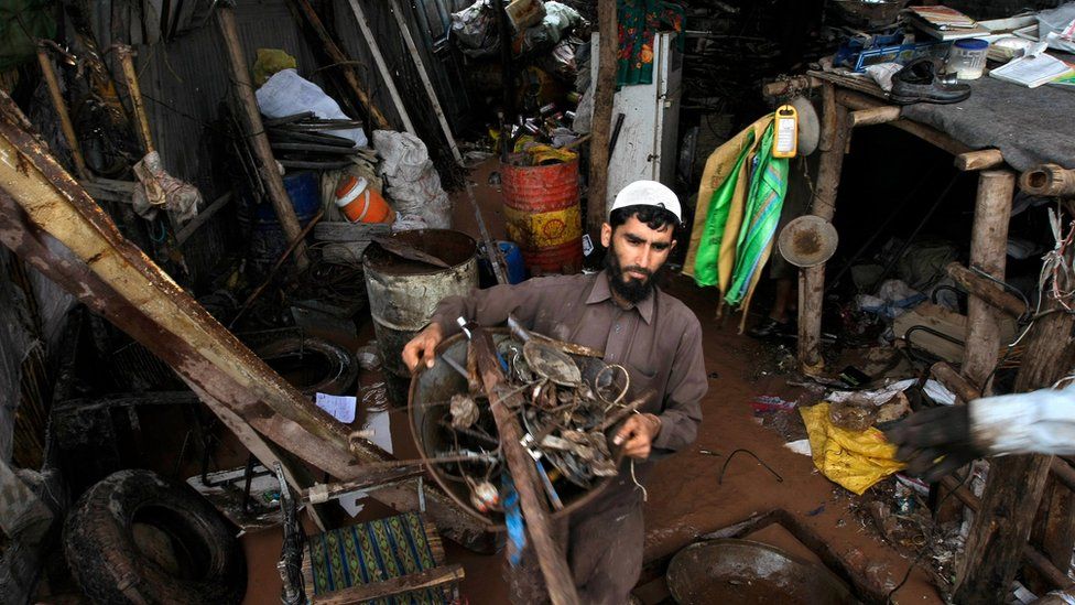 A Pakistani villager salvages his belongings from his flooded house