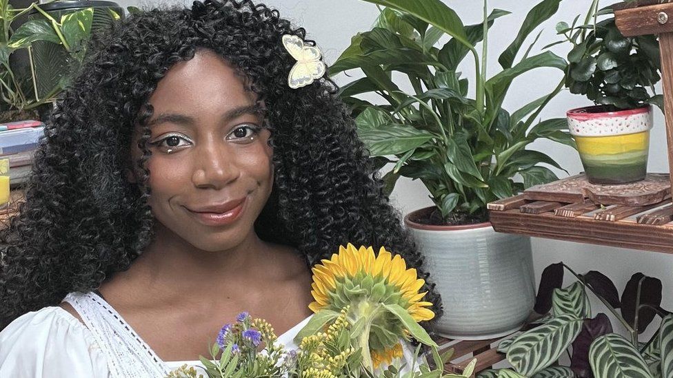 Climate Justice activist, Dominique Palmer surrounded by plants and flowers