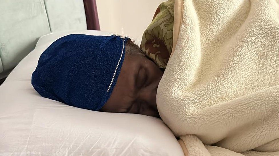 An elderly woman rescued from Sudan rests in bed.
