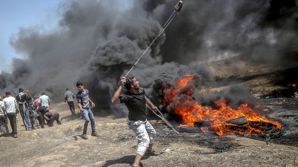 A Palestinian protester throws stones at Israeli troops during clashes after protests near the border with Israel in the east of Gaza Strip