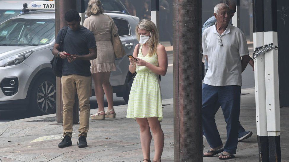A woman wears a face mask and a summer dress in Sydney's city centre