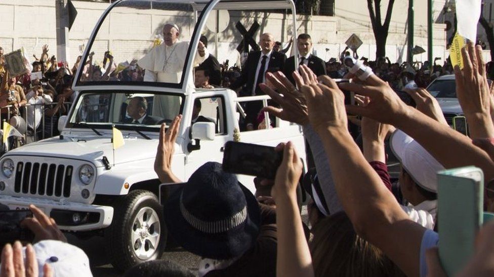 Pope Francis waves at the crowd from the Popemobile on his way to the Guadalupe Basilica