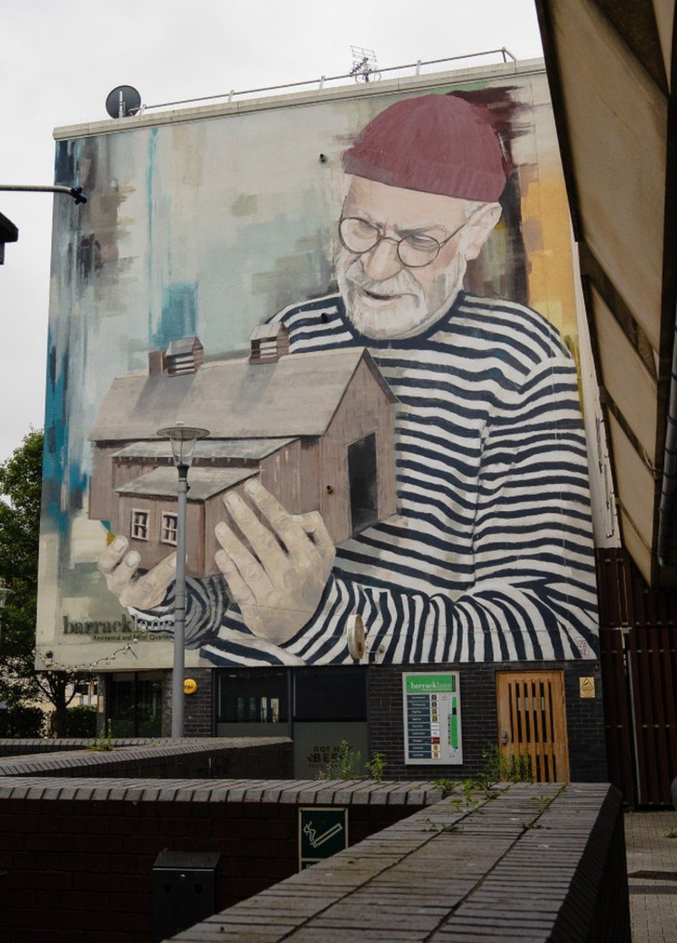 Homeless man holding house street art