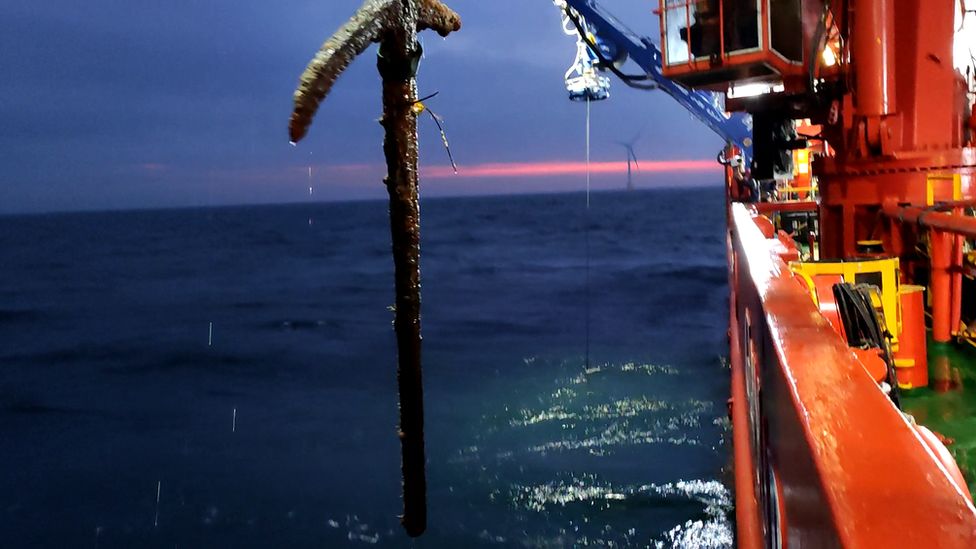 Wrought iron anchor being lifted from the sea