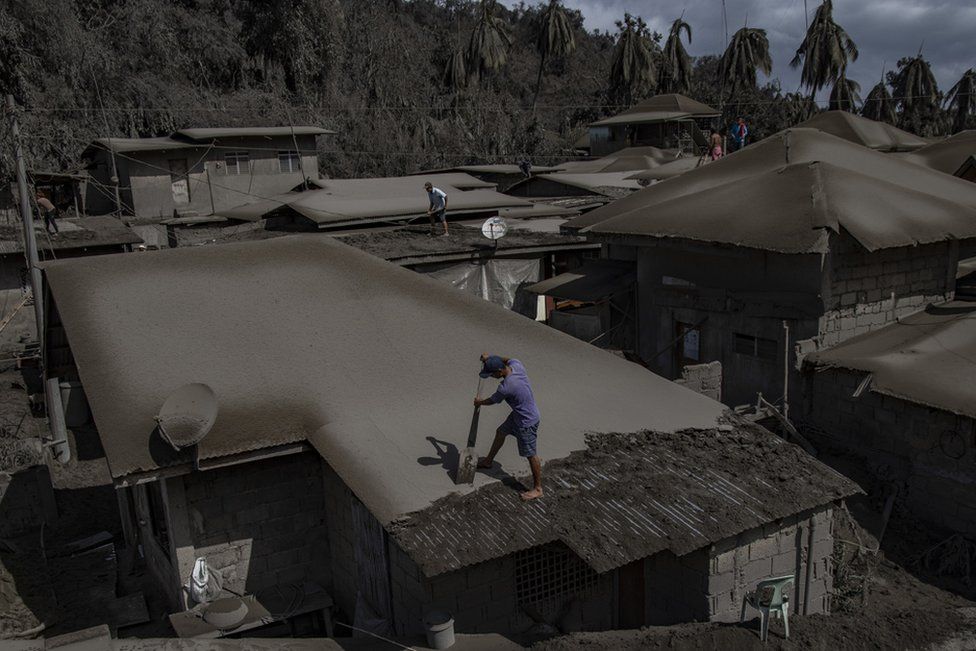 Residents clean rooftops of volcanic ash from Taal volcano's eruption in Laurel, Batangas province, Philippines
